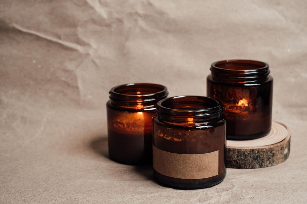 Three amber jar candles on a slice of wood
